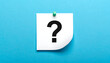 © fitri - Paper note with a black question mark pinned to a blue background, symbolizing uncertainty or inquiry