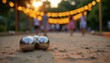 © Viktor - Metal balls rest on sandy court for bocce game at park. People play outdoor game under string lights at dusk. Evening leisure activity with friends.