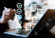 © wasan - Professional businessman using a laptop with digital checklist and document icons. This conceptual image represents task management, quality assurance, workflow automation, paperless office.