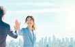 © -SAYONARA- - 都市を背景にハイタッチで喜びを分かち合う若手社員の爽やかなイメージ
