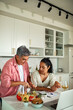 © Marko Geber - Couple cooking healthy dinner at home kitchen using a laptop recipe