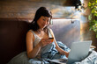 © Davor - Woman shopping online with credit card in bed at home