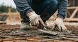 © Studio - A worker applying fresh concrete over a rebar grid with a trowel.Concept of reinforced concrete and construction work.