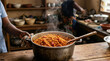 © Xenia - Steaming hot Jollof rice in a large metal pot on a wooden table. Traditional West African tomato rice dish. Culinary heritage and cooking concept