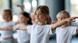 © Nataliya - Anonymous professional dance teacher training a group of children in a studio, youth dance education and selective focus concept, faceless, defocused, with copy space