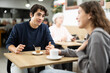 © JackF - Happy young guy and pretty girl on date over cup of coffee at table in small light cafe, face of guy and back of girl
