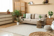 © Pixel-Shot - Comfortable sofa, rattan tables and houseplants in interior of living room
