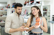 © JackF - is shopping at shoe store. Man helps girl choose toeless shoes, selects alternative options, shows cute models, and asks for companions opinion
