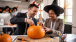 © Morrina - Halloween office teamwork celebration colleagues carving pumpkin together laughing for corporate newsletter magazine cover workplace culture promotion