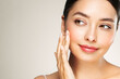 © Oleg Gekman - Skin care. Woman with beauty face touching healthy facial skin portrait. Beautiful girl model with natural makeup touching glowing hydrated skin on white background closeup