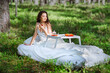 © Oleg Gekman - Woman wakes up in a summer forest. Young woman has breakfast in bed in a summer forest