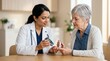 © iravgustin - Smiling medical professional showing blood glucose monitor results to an elderly senior patient, explaining diabetes control during a healthcare checkup consultation.