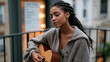 © forenna - Rain-soaked fire escape landing at evening where young musician practices deliberate skill repetition with acoustic instrument despite weather, habit streak calendar visible