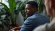 © Hasibnikon - Confident young Black professional man in denim shirt thinking indoors with tropical plants in soft natural light