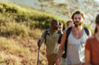 © Marko Geber - Friends hiking together on a sunlit hillside trail