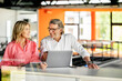 © Westend61 - Mature male professional sharing laptop with female colleague in office