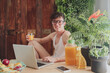 © Westend61 - Young man using laptop and drinking orange juice at home