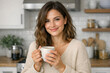 © vefimov - A woman with long hair smiling and holding a coffee cup in a kitchen.