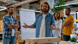 © Maksym - startup founder explaining company vision on rolling whiteboard to first five employees in empty office on move-in day, mismatched furniture and unpacked boxes surrounding early team, origin energy