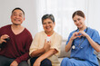 © NewSaetiew - Young Asian Female Nurse in Blue Scrubs with Stethoscope and Digital Tablet Consulting and Advising Happy Senior Asian Couple About Medication During Home Healthcare Visit.