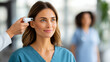 © Fox - Confident female healthcare worker in blue scrubs smiles as her temperature is checked with a digital thermometer in a modern medical facility. Professionalism and safety are emphasized