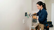 © Xenia - Female electrician wiring light switch with pliers and screwdriver. Professional woman repairing electrical outlet in home. Copy space for text