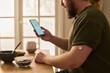 © Mediaphotos - Young man checking glucose app on smartphone while wearing continuous monitor at home, managing diabetes care. Useful for telehealth, chronic disease, wellness marketing