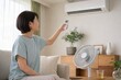 © AiPhoto - エアコンを調整する女性の夏の省エネ