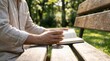 © MT - Young Caucasian man reading a book and drinking coffee on a wooden park bench in nature, representing a peaceful lifestyle, mindfulness, and leisure time activity