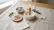© Sofiya - Candle lit on table with stones and wood decor