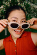 © Azamat Mukanov/Stocksy - Smiling woman in sunglasses portrait with blooming trees