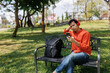 © Larissara Parn - A man in an orange shirt sat on a bench at a coffee shop. He was relaxing, chatting, reading a book, and working—a perfect example of a relaxed lifestyle.