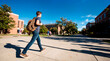 © Rendara Studio - College student walking briskly across sunny campus plaza with backpack