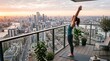 © Felippe Lopes - Woman practicing yoga on balcony overlooking city skyline at sunrise with arms raised in salute to the sun pose