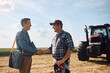 © Drazen - Happy farmer handshaking with insurance agent in field.