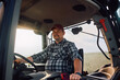 © Drazen - Happy agricultural worker in tractor looking at camera.