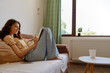 © SHOTPRIME STUDIO - Woman relaxing on a sofa at home, using a tablet, soft daylight from a window, casual mood, cozy interior, serene atmosphere, comfortable posture, lifestyle setting