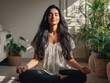 © The Little Hut - Serene young woman meditating peacefully in lotus position indoors, bathed in warm sunlight with houseplants