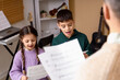 © Pixel-Shot - Young children learning music with teacher, singing from sheet music, music education and childhood development