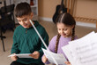 © Pixel-Shot - Young boy and girl learning music together, reading sheet music for early childhood education and musical development