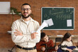 © Pixel-Shot - Smiling male music teacher holding sheet music with young students learning guitar in classroom, music education and skill development are fostered in a classroom setting