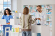 © Pixel-Shot - Pharmacist and pharmacy technician assisting customer with prescription and healthcare products at modern drugstore counter