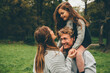 © Westend61 - Happy young couple with little girl on her father's shoulders at autumnal park