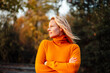 © Westend61 - Woman looking away while standing with arms crossed during sunset