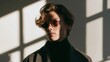 © CYBERPINK - Portrait of a young man wearing sunglasses. he is standing in front of a white wall with large windows that let in natural light.