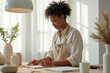 © YouraPechkin - Young Black Woman Writing and Creating in a Bright Studio