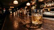 © Wednesday - Glass of whiskey with ice on a wooden bar counter in a blurred nightclub