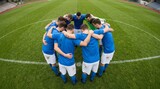 Team huddles together on a green field before a match