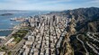© VhayzR - Aerial view of a modern coastal metropolis with dense downtown skyscrapers bordered by ocean bay and mountain range