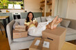 © Home-stock - Lady surrounded by parcel boxes browsing cellphone, enjoying convenience of online shopping and home delivery, sitting on sofa in living room
